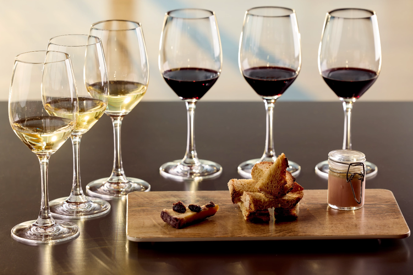 White and red wine glasses with accompaniment dish, on the terrace of the cafe